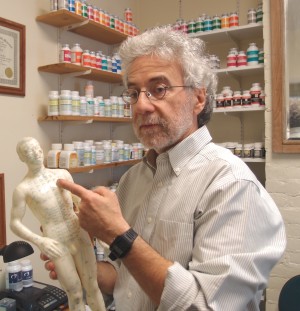 Acupuncturist Ron Hershey holds model used to point out acupuncture channels of vital energy.