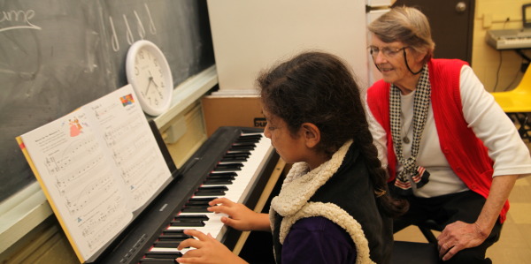 Sister Beth Dowd at a piano with Ariana Barrios.