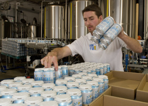 Jordan Giles stacks completed six-packs of Bright Ale on a pallet at Half Full Brewery in Stamford in May. The brewery was among 10 Stamford companies that reported raising a combined $37.8 million in financing last year to the Securities and Exchange Commission. Photo by Lindsay Perry