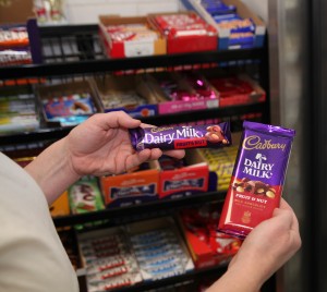 In front of her store's candy shelf, Mary Slater compares the European Cadbury bar, left, to its American counterpart. Photo by Danielle Brody