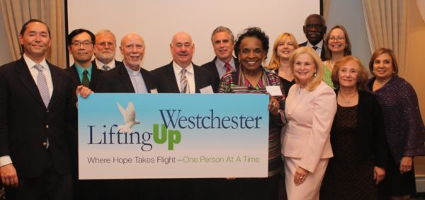 Lifting up Westchester members, including Linda Gallo, third from right in the first row, and Paul Anderson-Winchell, first from left in the back row, unveil the nonprofit's new name and brand identity.