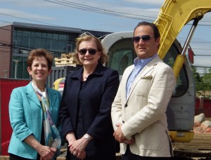 From left, Sacred Heart University”™s Ellen Kovar, Mary Lou DeRosa and John DeBenedictis beside a dorm under construction. The Frank and Marisa Martire Business and Communications Center is behind them. Photo by Bill Fallon