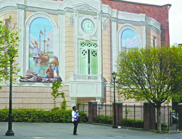 A Yonkers resident waits for a bus in front of a Richard Haas mural panel at 36 Main St. Photo by John Golden