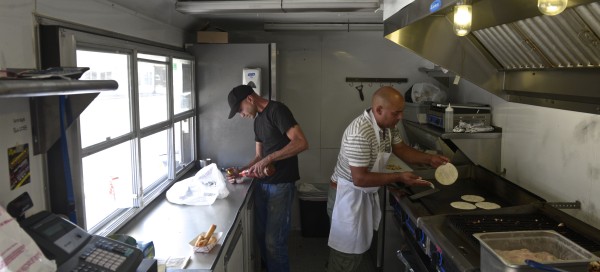 Leonardo Almonte, left, and Freddy Avames fill an order in Almonte's food truck, Meat the Press, on White Street in Danbury. Photo by H. John Voorhees III 