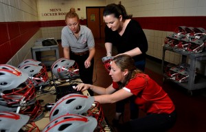 Uploading data from lacrosse helmet sensors are, from left, athletic training student Sydney Judkins; Prof. Theresa Miyashita, director of the athletic training program; and Kaitlyn Marrie, head athletic trainer for the men's lacrosse team. Photo by Tracy Deer-Mirek