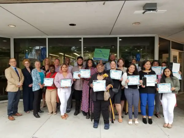 Bootcamp graduates pose with their graduation certificates.