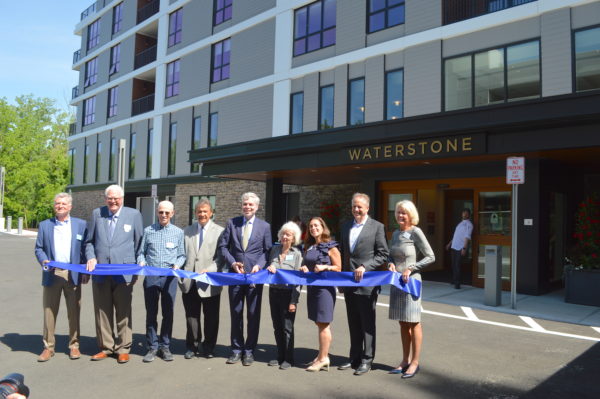 Ribbon-cutting for Waterstone of Westchester with White Plains Mayor Tom Roach holding scissors and County Executive George Latimer to the left.